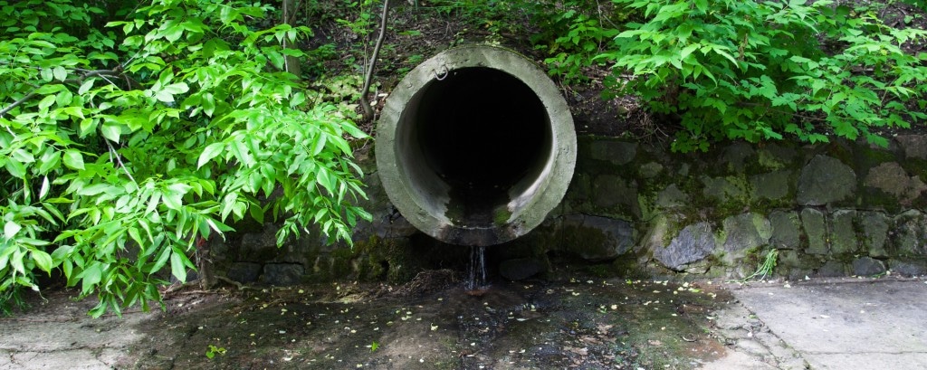 The concrete circular run-off pipe discharging water
