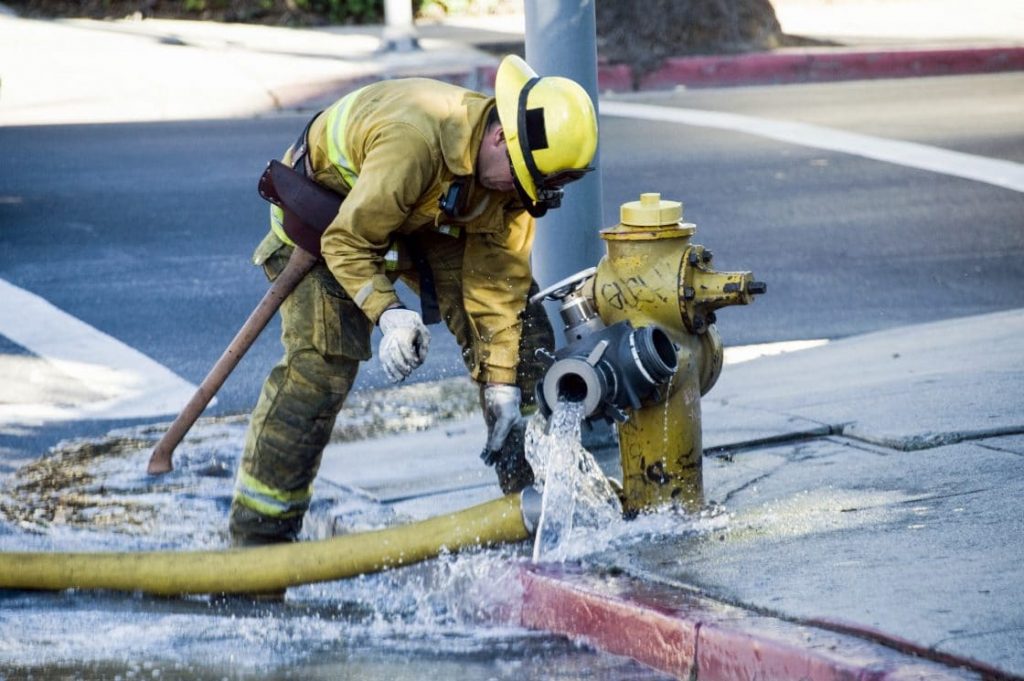 firefighter attaching hose to hydrant