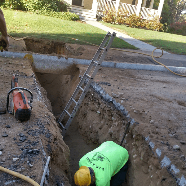 Lead service replacement program in Newton, MA. Excavator and men. Construction worker replacing pipes.