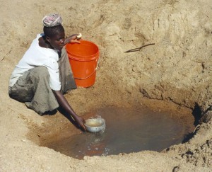 A woman in Mwamongu fetches water from an unimproved source.